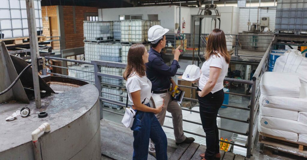Profissionais analisando processo industrial em ambiente fabril durante atividade de gestão e controle ambiental